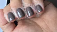 Glossy taupe manicure resting on linen