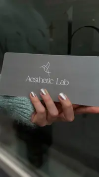 Silver manicure holding an Aesthetic Lab card